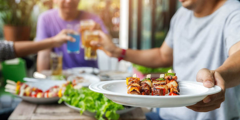 A man grills skewers with vegetables and meat.